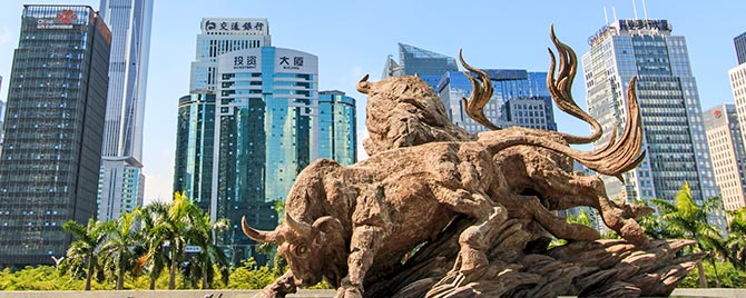 Chinese cityscape in background with bull sculpture in foreground