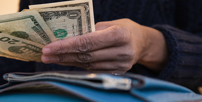 Hand holding U.S. dollar bills.