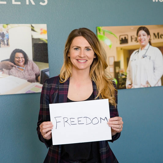 Woman smiling with an oversized card reading: freedom