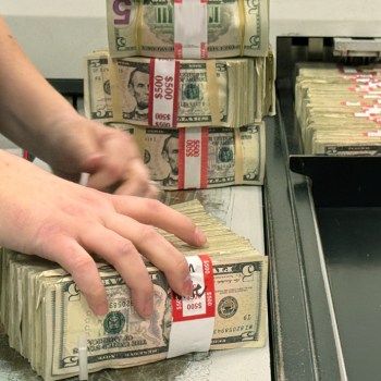 Person handling stacks of five dollar bills.