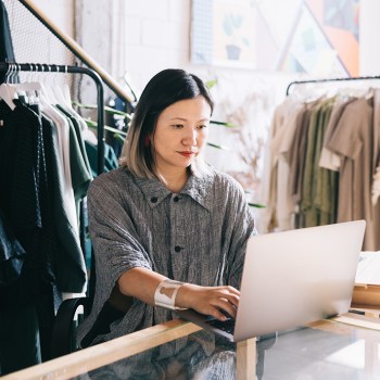 Female clothing shop owner uses her laptop to manage orders