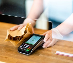 Cashier wearing gloves while accepting payment for pastry