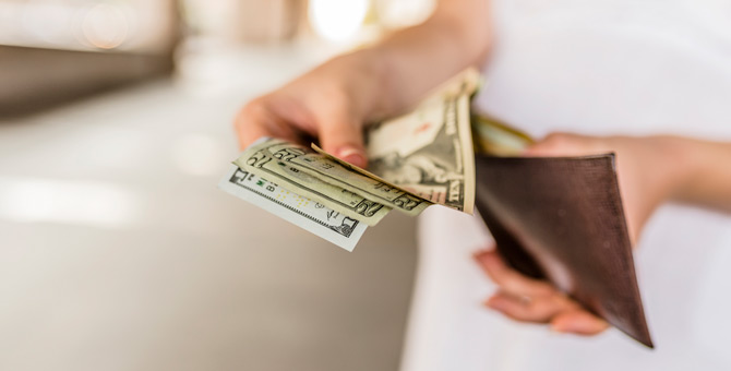 Person putting dollar notes into a wallet