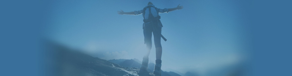 Mountain climber looking up at the sky with arms outstretched