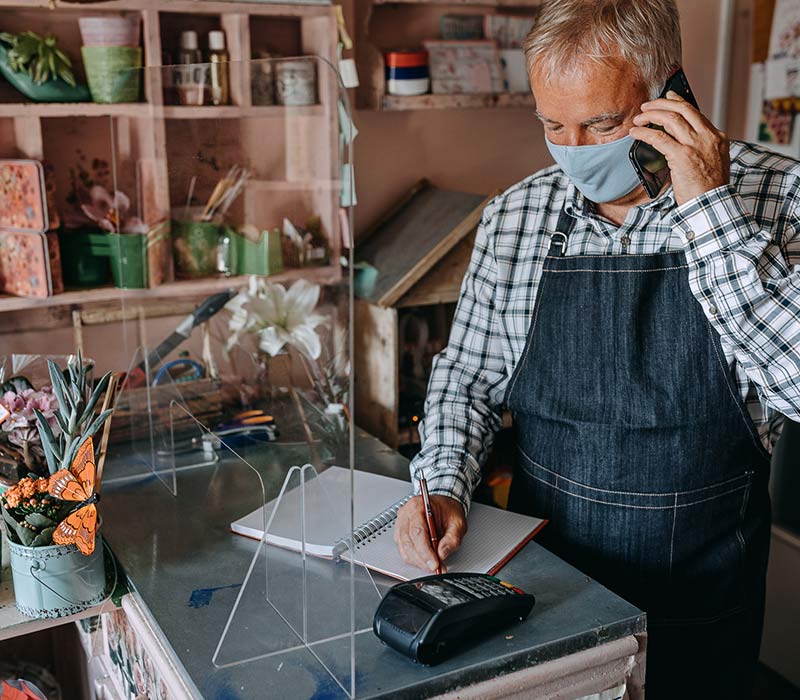 Florist with protective face mask talking on phone and taking an order