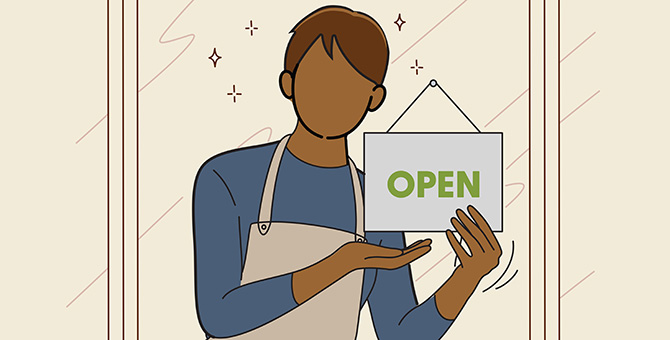 An employee inside of a shop holding up an 'OPEN' sign