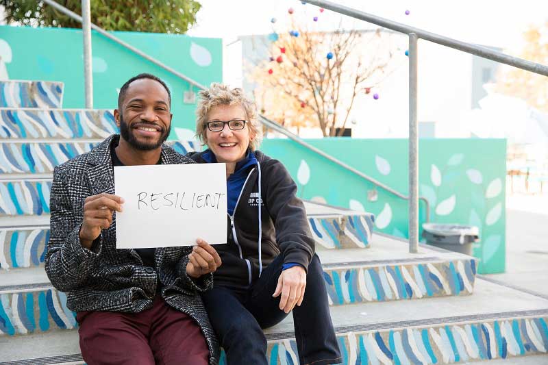 Fredrick Alexander, with President Daly, holds sign reading Resilient