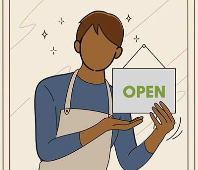 An employee inside of a shop holding up an 'OPEN' sign