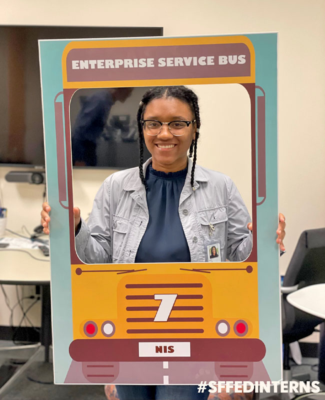 Faith holding up a sign for Enterprise Service Bus, a team under the National Solution Services Group.