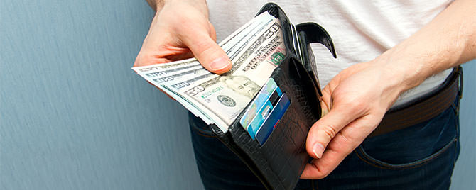 Photo of man holding wallet with cash credit cards