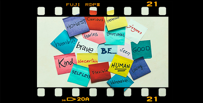 Sticky note with ‘Be…’ in the center of other notes with words including: seen, human, curious, uncertain, loving, kind