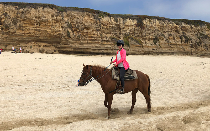 Min Wang horseback riding along the beach