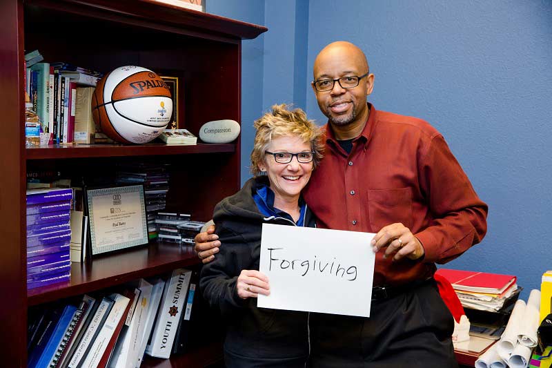 Pastor Paul Bains, with President Daly, holds sign reading Forgiving