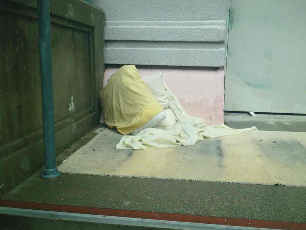 A sleeping space with blanket and pillow in corner