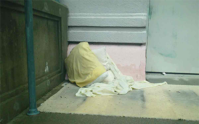 A sleeping space with blanket and pillow in corner