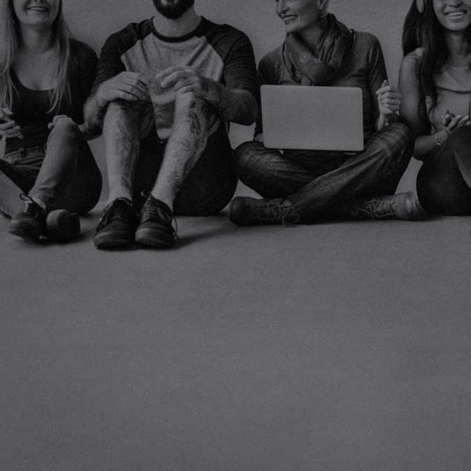 Diverse group of young men and women sitting on the ground, smiling and conversing